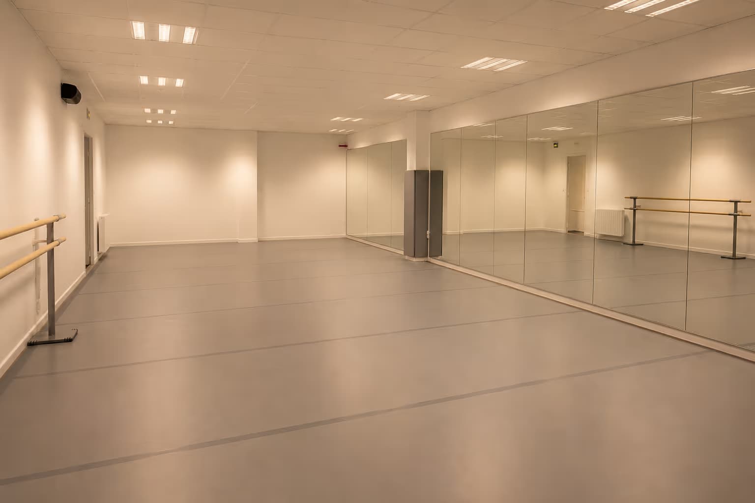 Danseuse en plein mouvement dans une salle de danse au parquet clair, lumière chaude